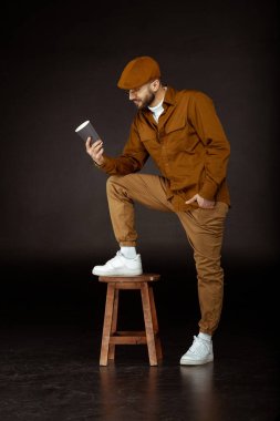 Bej renkli şapka ayakta tek bacaklı sandalyeye ciddi adam