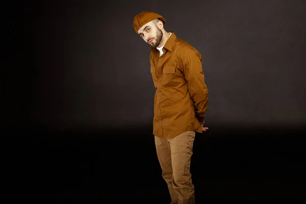 Hipster hombre vistiendo sombrero beige y camisa sostiene las manos detrás de su espalda — Foto de Stock