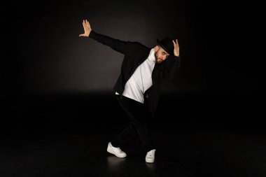 Bir şık siyah elbise giymiş yakışıklı adam sokak dansı dans ediyor