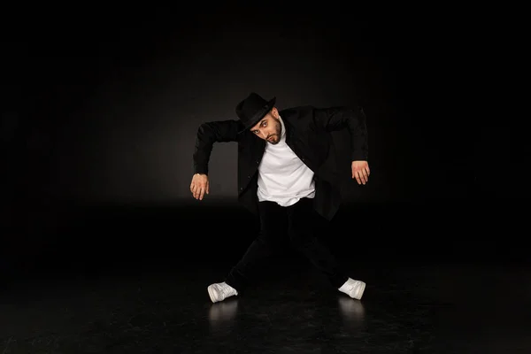 Hombre guapo vestido con una elegante ropa negra está bailando danza callejera — Foto de Stock