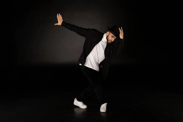 Knappe man, gekleed in een stijlvolle zwarte kleding danst Streetdance — Stockfoto