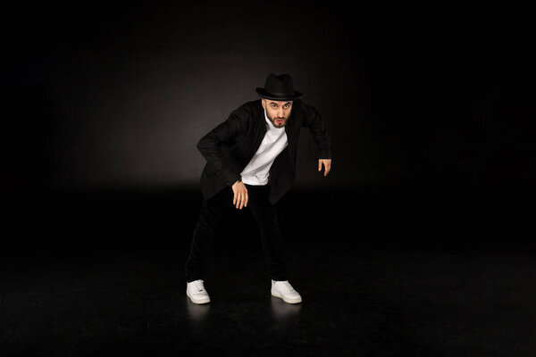 Young male modern dancer in black clothes and hat