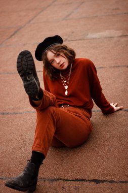 Model poz. Kıvırcık saçlı profesyonel Foto model kırmızı pantolon ve kazak giyiyor