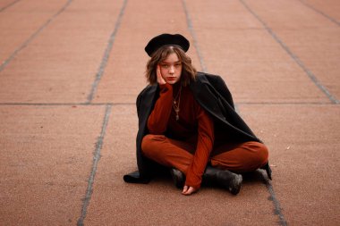 Kırmızı pantolon ve kazak yerde oturan genç kıvırcık kız