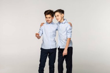 İki genç erkek kardeş kısa saçlı mavi gömlek portresi, bir tane değil, kardeşine gösteren somesing işaret ediyor