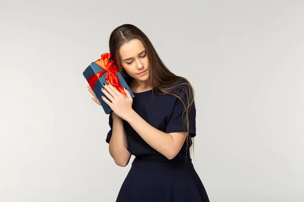 Досить молода дівчина в темній сукні тримає подарункову коробку — стокове фото