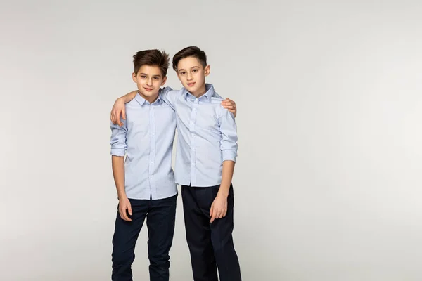 Unga bröder i blå tröjor kramas i studion — Stockfoto