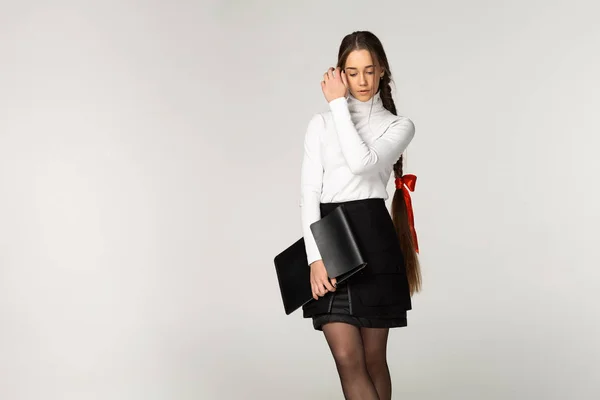 Innenporträt eines attraktiven jungen Mädchens mit Zopf und roter Schleife — Stockfoto