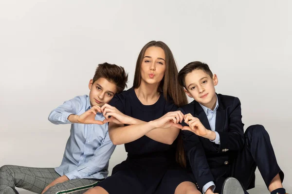 Hermosa hermana sentada en el suelo con dos hermanos menores —  Fotos de Stock