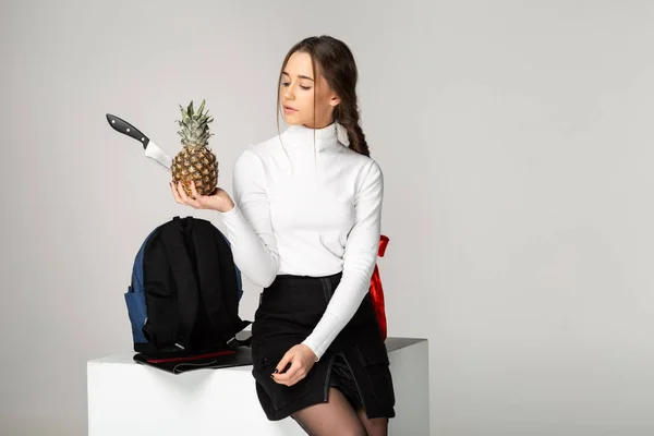 Trendiga ung flicka håller i hennes händer ananas med kniv — Stockfoto