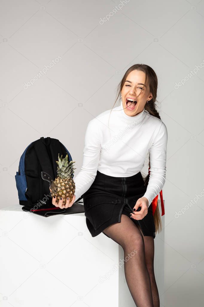 Emotional young girl student holding in hand pineapple with knife inside