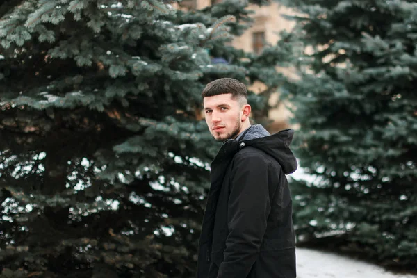 Hadsome joven en tela de invierno de pie en el parque — Foto de Stock