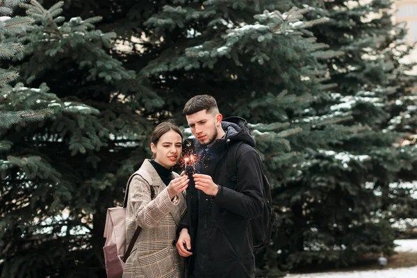 Romántica pareja joven se divierte al aire libre en invierno antes de Navidad con luces de bengala — Foto de Stock