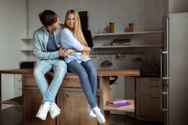 Mutlu genç kaç mutfakta oturan mavi kot kumaş içinde gülümseyen