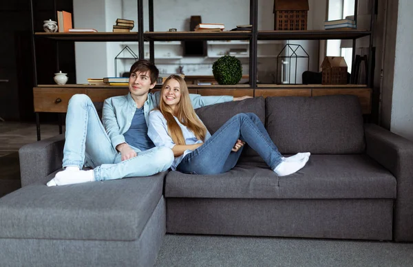 Retrato em tamanho completo de atraente casal na moda sentado no moderno apartamento de espaço aberto — Fotografia de Stock