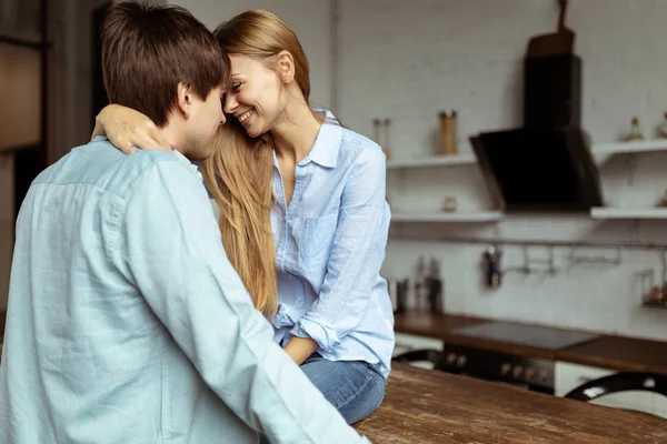 Happy hispanic couple in blue denim cloth embracing in kitchen — Stock Photo, Image