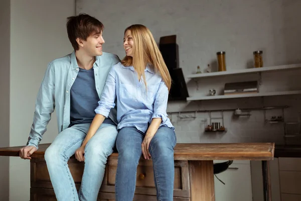 Young beautiful couple in blue denim cloth sitting in the kitchen — Stock Photo, Image
