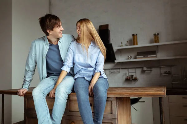 Joven hermosa pareja en tela de mezclilla azul sentado en la cocina — Foto de Stock