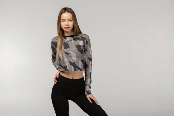 Young passen mooie vrouw in de sport kleding tegen grijs baclground — Stockfoto