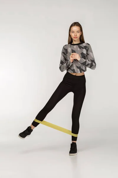 Gesunde Frau mit gutem Körperbau beim Stretching mit Gummibändern — Stockfoto