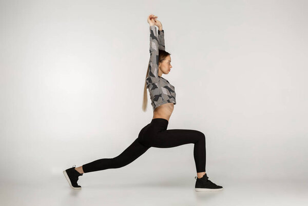 Young sporty attractive woman practicing yoga doing reverse warrior exercise