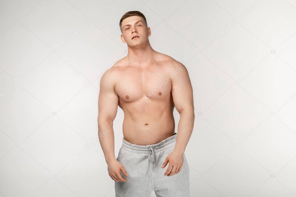 Half length portrait of young physically fit man showing his well trained body