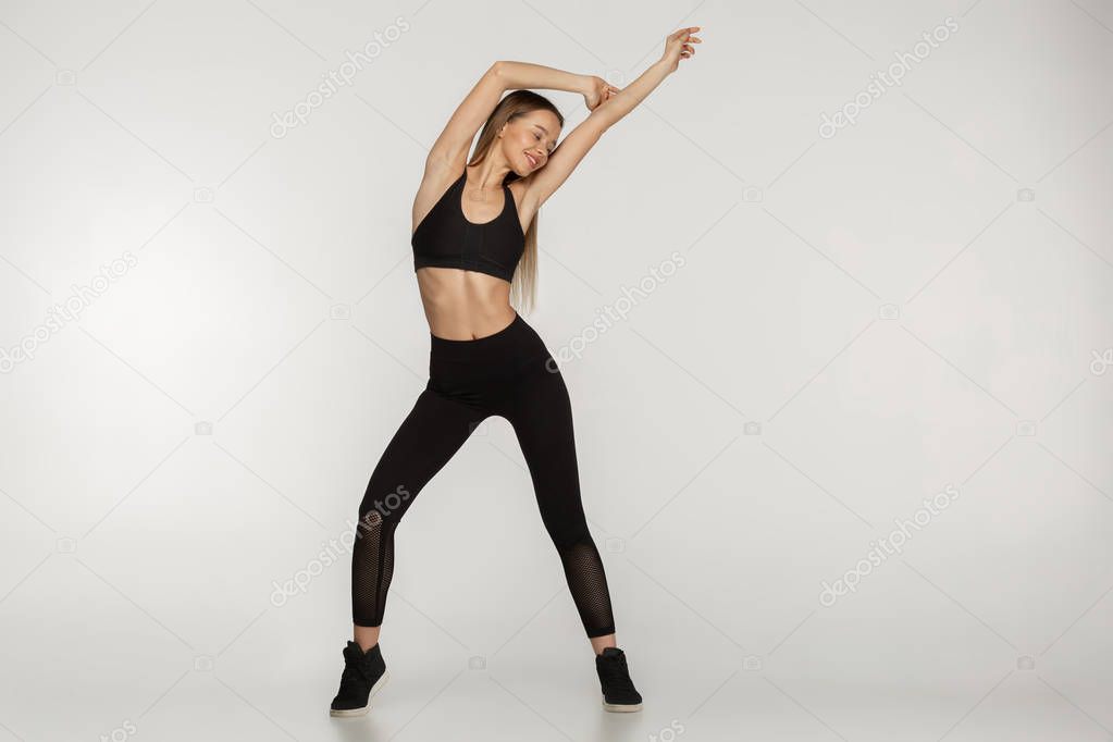 A full length portrait of a sporty woman in stylish black sportwear
