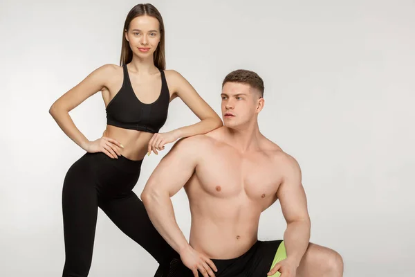 Hemdloser muskulöser Mann mit nacktem Oberkörper auf einem Knie stehend und schönem, sportlichem Mädchen an ihn gelehnt — Stockfoto