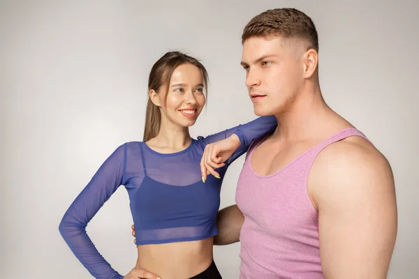 Молодая спортивная девушка в синем топе опиралась на своего партнера по фитнесу в розовой футболке — стоковое фото