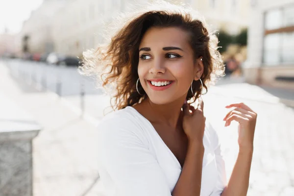 Jeune femme frisée brune expressive avec bronzage et naturel faire upwalking dans la rue — Photo