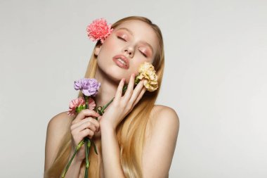 Bahar çiçekleri elinde tutan kapalı gözlü sarışın kız
