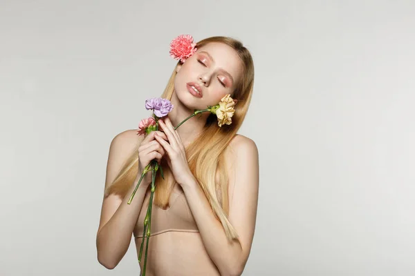 Primavera menina loira com olhos fechados segurando flores nas mãos — Fotografia de Stock