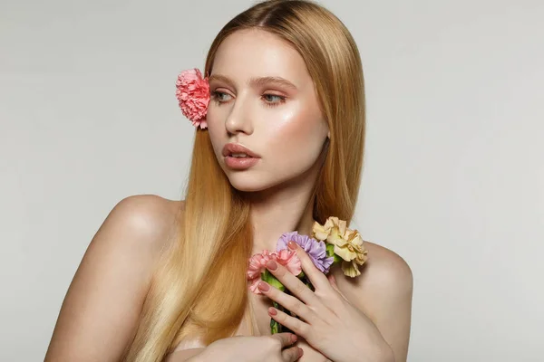 Encantador modelo femenino con piel perfecta sosteniendo flores en la mano — Foto de Stock