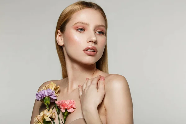 Encantador modelo femenino con piel perfecta sosteniendo flores en la mano — Foto de Stock