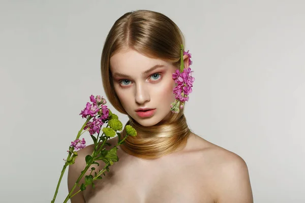 Vacker ung kvinnlig modell med blå ögon, perfekt hud med blommor på axeln — Stockfoto