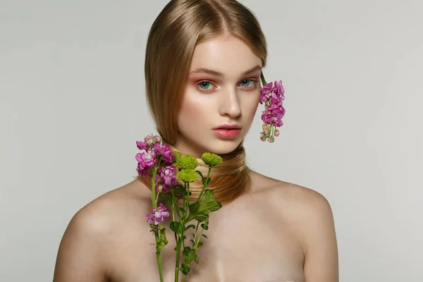 Vacker ung kvinnlig modell med blå ögon, perfekt hud med blommor på axeln — Stockfoto