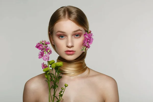 Ganska ung kvinna med färsk våren titt, fantastiskt hår, fin makeup blommor nära ansiktet och i håret — Stockfoto