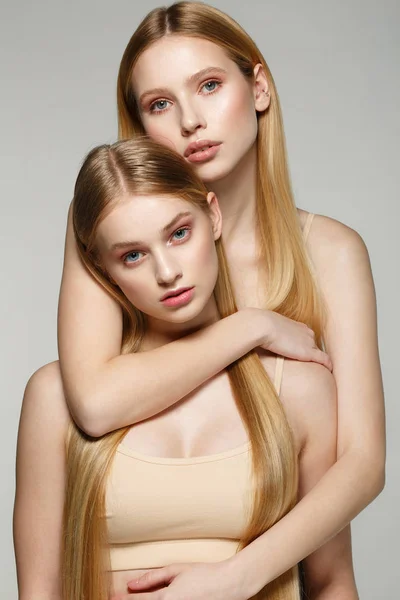 Deux belles sœurs jumelles filles avec les mêmes cheveux longs blonds et la peau parfaite — Photo