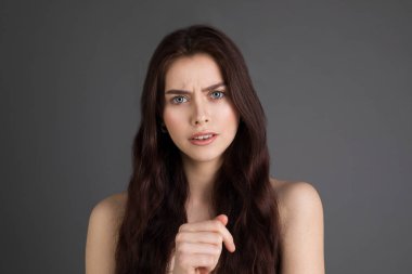 Çıplak omuz ile hoşnutsuzluğunu yüzüne çatık esmer saçlı güzel kız portresi kapatın