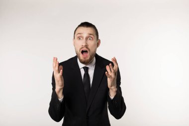 Siyah takım elbise ve kravat beyaz arka plan üzerinde çekici yakışıklı sakallı adam sürpriz ve şok yüz ifadesi