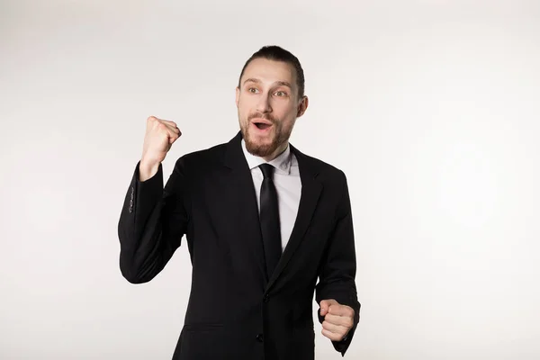 Ja. Winnaar. Elegante jonge man staan en gesturing voor de overwinning op witte achtergrond in zwart pak en stropdas — Stockfoto