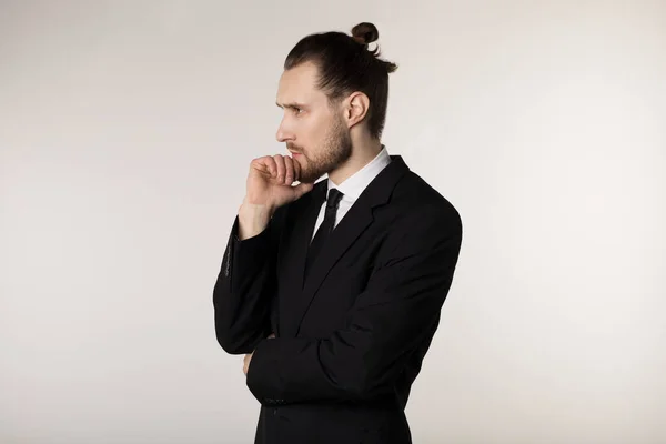 Retrato de vista lateral de joven empresario atractivo en traje negro con peinado elegante cogido de la mano en la barbilla con expresión reflexiva — Foto de Stock