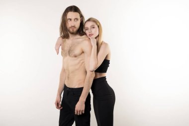 Genç çift, uzun saçlı ve çıplak gövde ile sakallı adam ve doğal makyaj ile güzel kız stüdyoya poz verirken sarılma