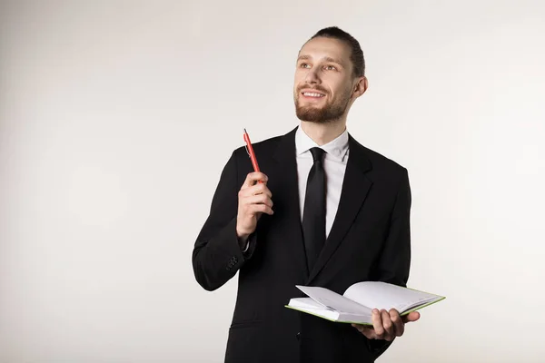 Joven atractiva profesora barbuda en traje negro y corbata sosteniendo cuaderno y pluma en las manos — Foto de Stock