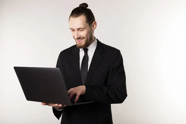 Young handsome businessman with beard and trendy hairstyle wearing black suit and tie — Stock Photo, Image