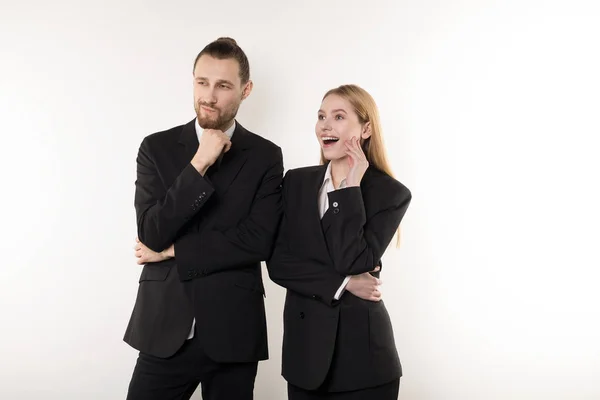 Dos empleados felices en trajes negros de pie junto con las manos en la cintura mirando la presentación de su jefe — Foto de Stock