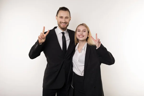 Dos empleados se ríen alegremente al final de la semana laboral, mostrando un signo viktory y mirando a la cámara — Foto de Stock