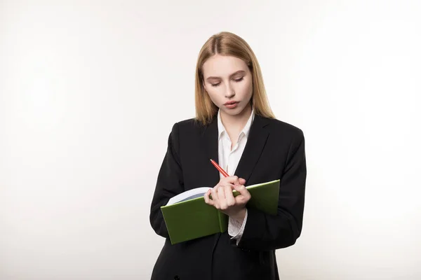 Cintura hasta tiro de mujer de negocios rubia seria en traje negro que escucha atentamente a su socio de negocios y toma notas en un cuaderno — Foto de Stock