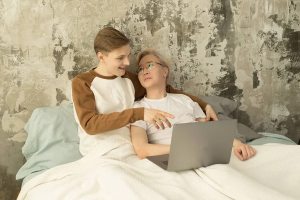 Unga internationella samma kön manliga par tillbringa tid tillsammans i en säng tittar på laptop — Stockfoto