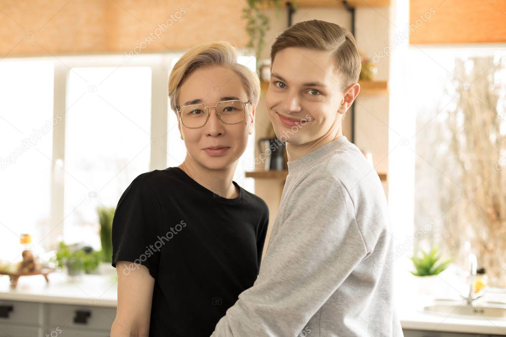 Close up portrait of two young international gay men in casual clothes, one asian blonde men in eyeglasses, seon european with brown hair